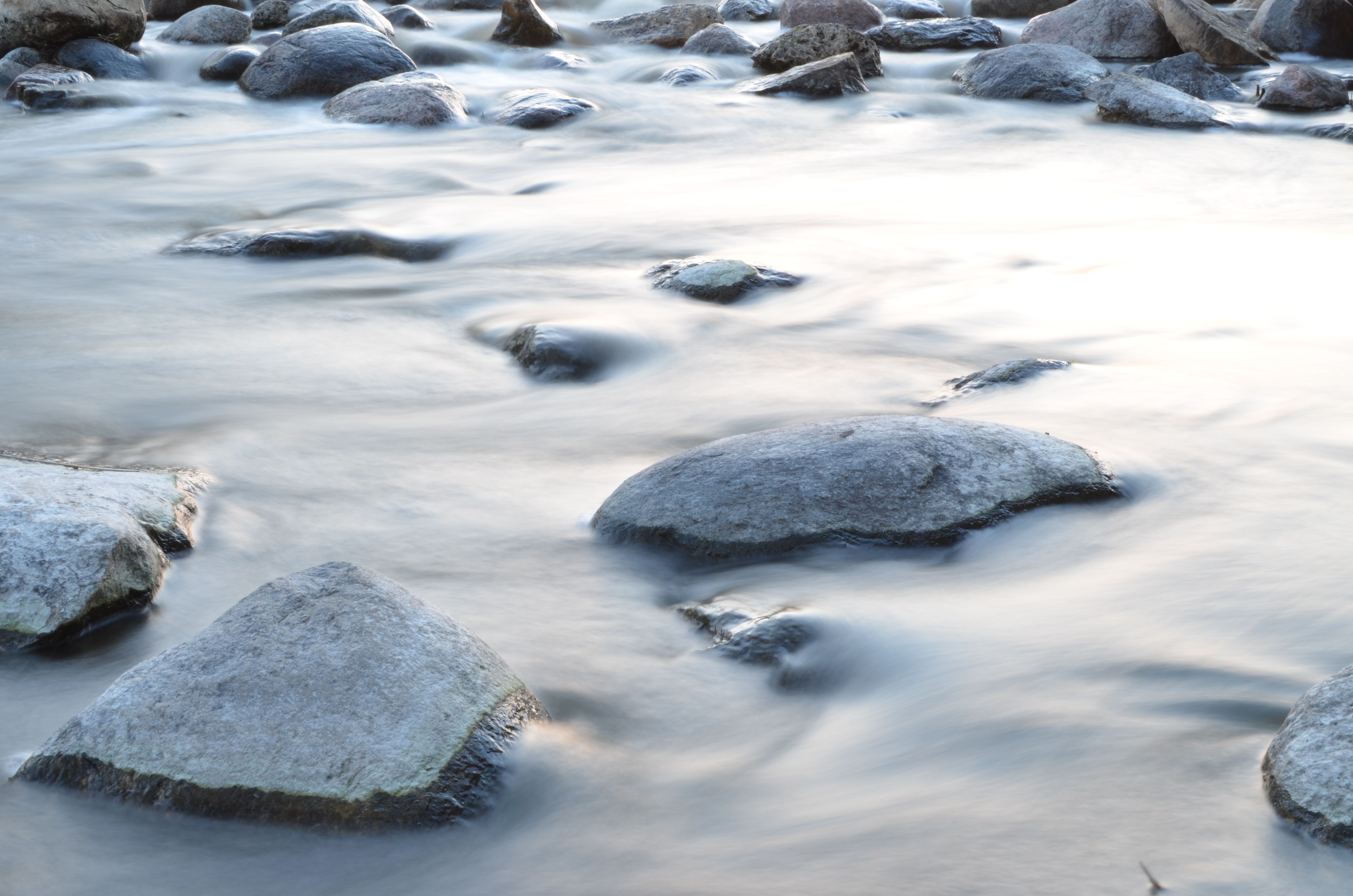 Long exposure of water flowing over granite boulders, shot on a northern river